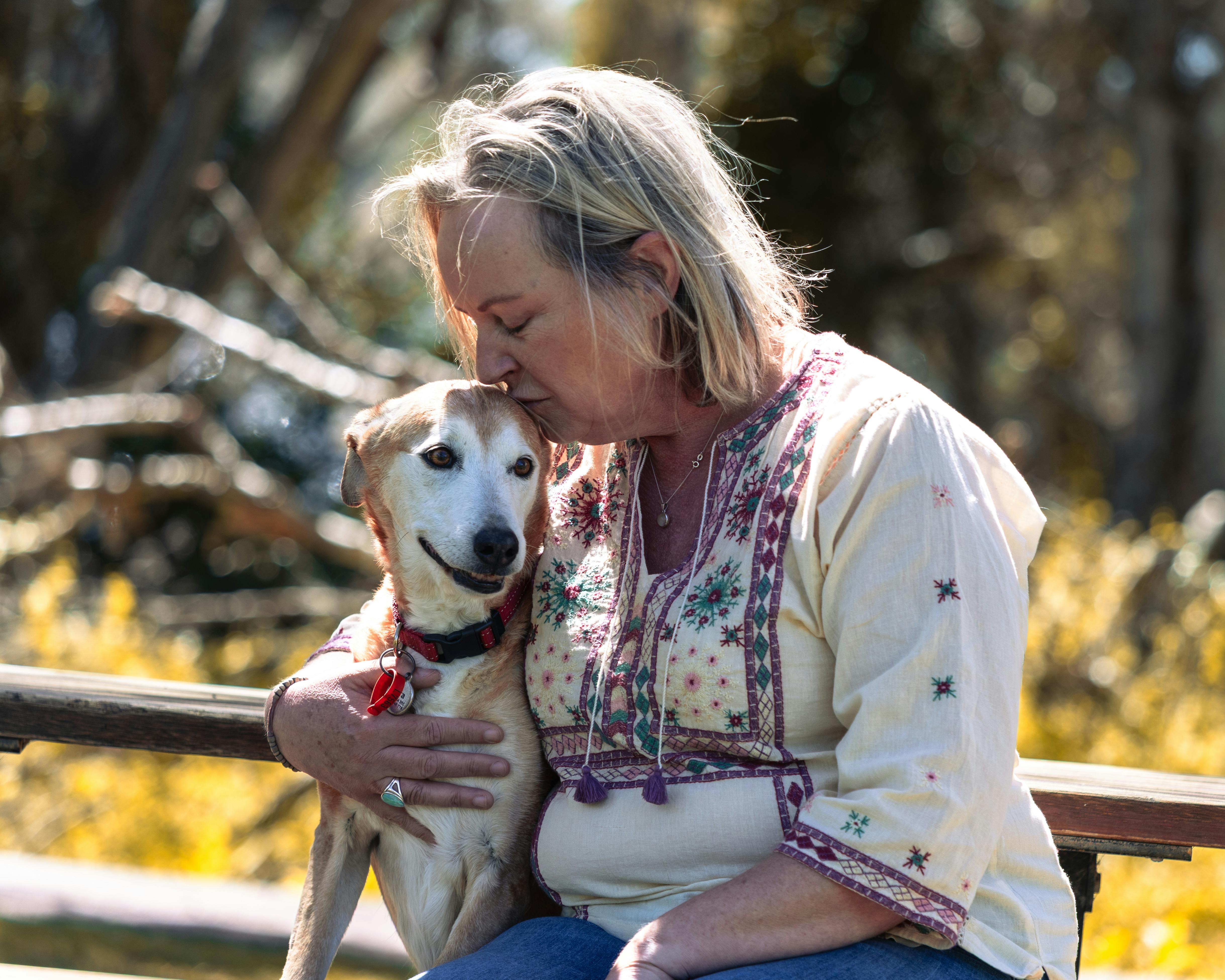 Woman kissing her senior dog — reasons to adopt